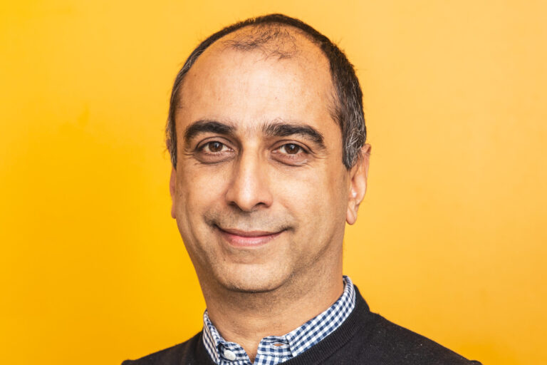 Headshot of Nikhil Anand against a golden yellow background.